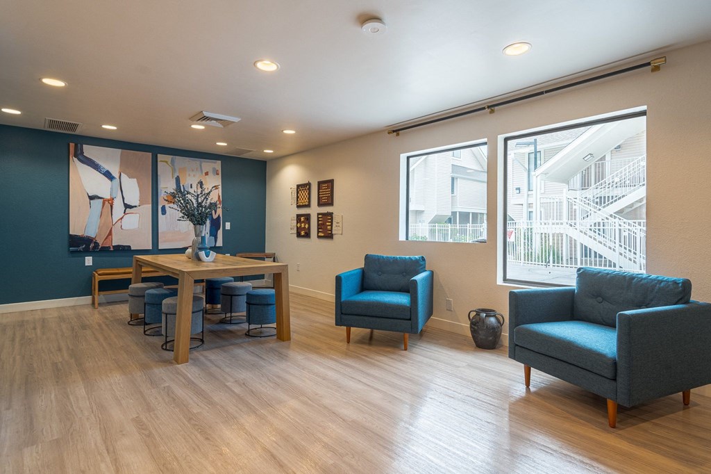 a waiting room with blue chairs and a wooden table with a vase of flowers